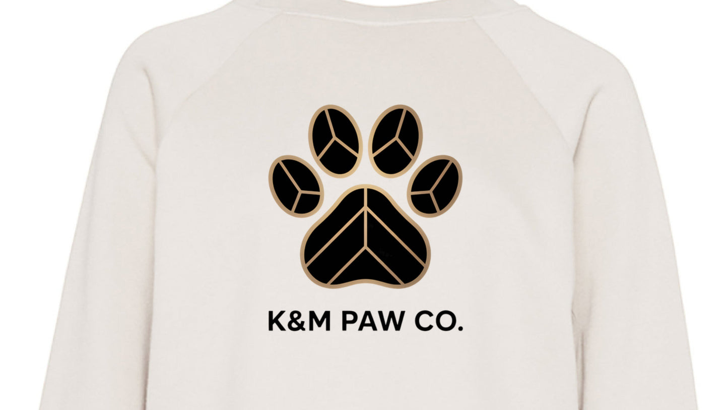 Cream cropped luxe sweater featuring the K&M Paw Co. black and gold paw print logo, part of the Paw Print Luxe Collection, designed for stylish pet lovers seeking premium quality and modern elegance